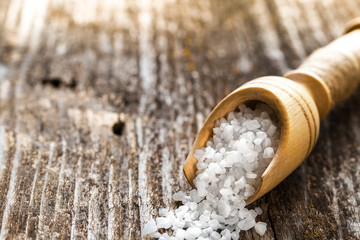 Sea salt  in a spoon on wooden table.