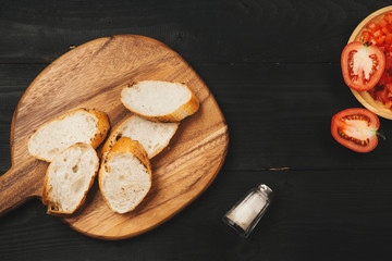 Preparing delicious Italian tomato bruschetta with chopped vegetables, herbs and oil