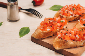 Italian bruschetta with roasted tomatoes, mozzarella cheese and herbs on a cutting board