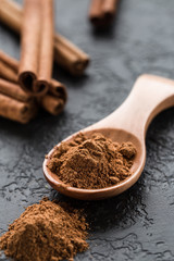 ground cinnamon spice powder in wooden spoon
