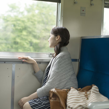 電車に乗り景色を眺める女性