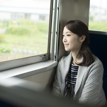 電車に乗り景色を眺める女性