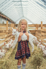 happy child holding goat at farm and looking at camera