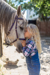 side view of preteen kid hugging horse at farm