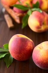 Fresh ripe peaches, photographed on dark wood with natural light (Selective Focus, Focus on the front of the front left peach)