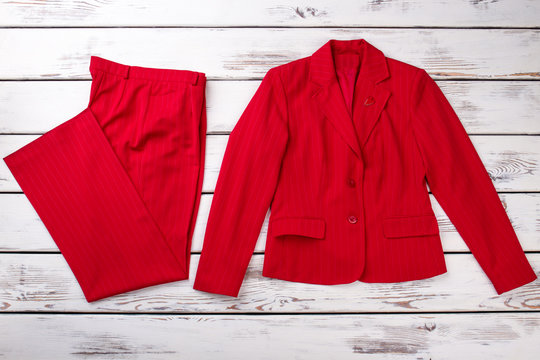 Flat lay red women suit. Trousers and jacket. Bright wooden desks surface background.