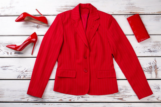 Red feminine jacket, shoes and wallet. Flat lay, bright wooden desks surface background. Top view.