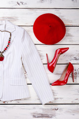 Flat lay red berete and shoes. White jacket. Wooden desks surface background.