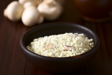 Instant mushroom soup powder in rustic bowl, photographed on dark wood with natural light (Selective Focus, Focus one third into the soup powder)