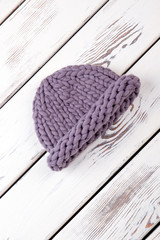 Warn winter knitted hat. White wooden desks surface background.