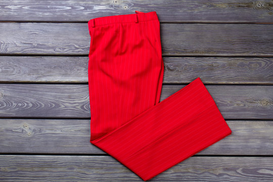 Folded Red Women's Trousers. Grey Wooden Surface Background. Flat Lay, Top View.