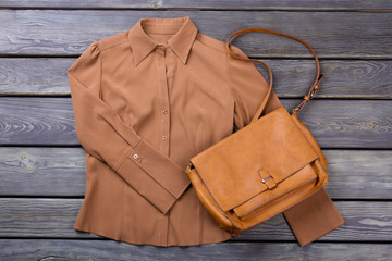 Brown shirt and purse. Flat lay, top view. Grey wooden surface background.