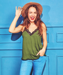 Young stylish girl model in casual summer green clothes and brown hat with red lips, posing near...