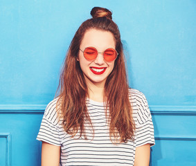 Young stylish girl model in casual summer clothes with red lips, posing near blue wall. Happy, and closed eyes