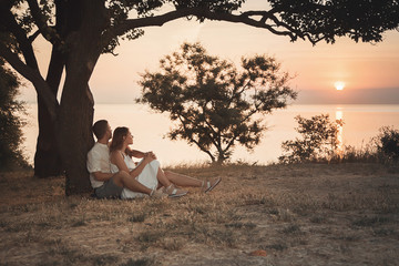  Beautiful scenery at dawn. A beautiful tree in the shape of a heart symbol. A loving couple sits hugging under a tree.