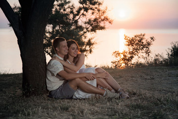 A couple is sitting under a tree. Lovers embrace at dawn.