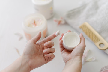 Young woman's hands holding white cream jar