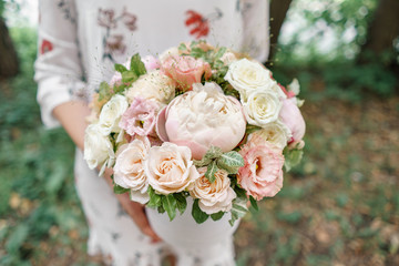 Beautiful summer bouquet. Arrangement with mix flowers. Young girl holding a flower arrangement with peony. The concept of a flower shop. Content for the catalog