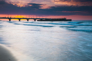quiet beach with pier at sunset, long time exposure