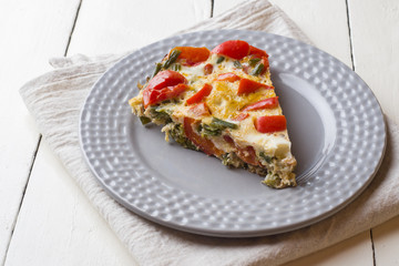 Omelet serving with vegetables on a plate on a white wooden table