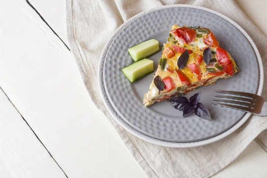 Omelet serving with vegetables on a plate on a white wooden table. Copy space