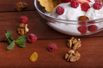 melted ice cream in transparent bowl, decorated with strawberrie, raspberries and biscuit