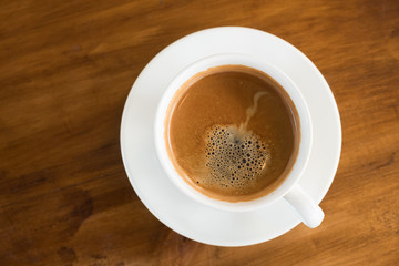 top view hot coffee in the white cup on wooden table.