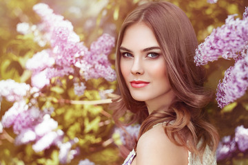 Fototapeta premium Beautiful Woman with Flowers of Lilac. Spring Blossom. Sexy Glamour Summer Beautiful Lady with Healthy and Beauty Hair