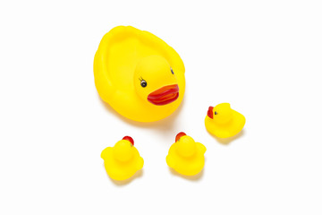 Rubber toy of yellow color Mama duck and little ducklings look at it on a white background. Concept of maternal care and love for children