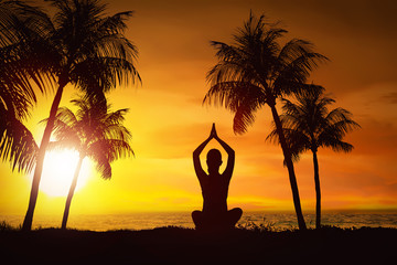 Silhouette of woman doing yoga with ocean view