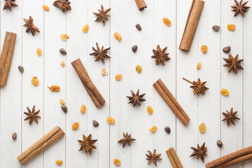 Obraz na płótnie Canvas Background of cinnamon sticks, star anise, nuts and raisins on white wooden table.