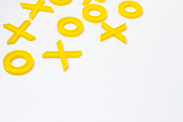 Yellow plastic figures for playing tic-tac-toe on a white background