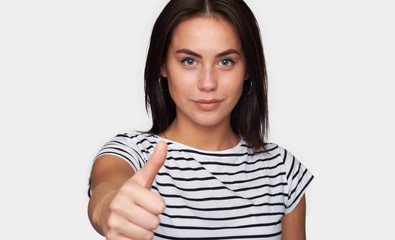 smiling young woman showing thumbs up