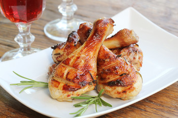 Grilled chicken legs with rosemary served on white plate. Dinner background