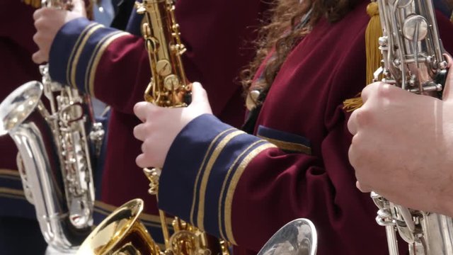 Close up of several unrecognizable saxophone marching band members playing in a row