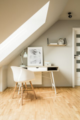 White chair standing by the wooden desk with pastel lamp and sim