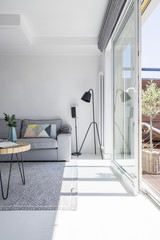 Real photo of white living room interior with grey couch, black