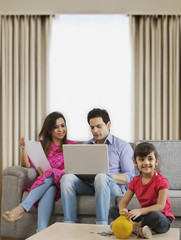 Little girl sitting with piggy bank and parents looking home finances 