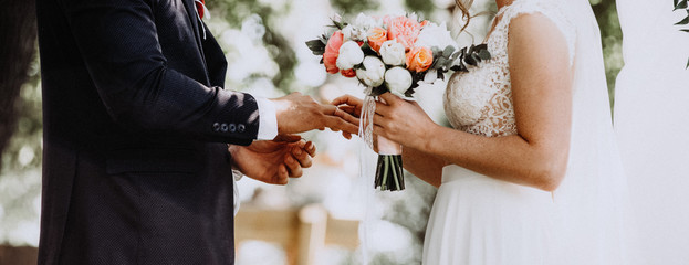 Wedding ceremony. Newlyweds exchanging rings, bride putting the ring on the groom's hand.