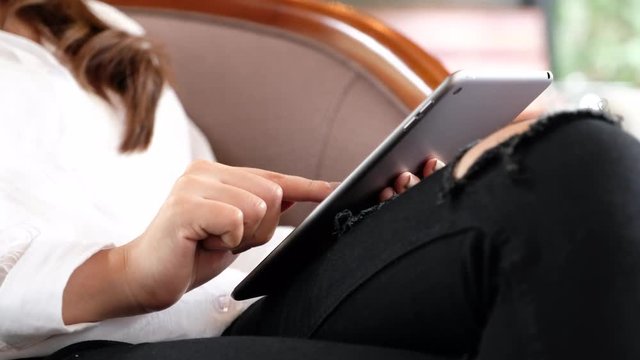 A woman holding , using and sliding touch screen tablet pc in modern cafe