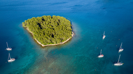Fototapeta premium Aerial view of sailing boats anchoring next to small island