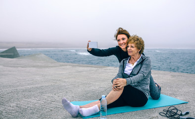 Personal trainer taking selfie with senior woman by sea pier