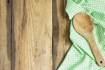 Wooden spoon and green cloth on an old wooden kitchen table