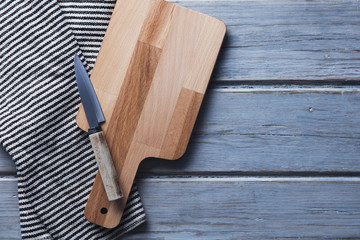 Wooden chopping board and cloth on a rustic wood plank table
