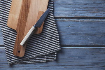 Wooden chopping board and cloth on a rustic wood plank table