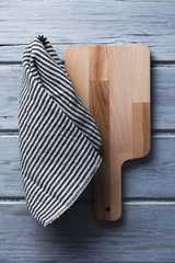 Wooden chopping board and cloth on a rustic wood plank table