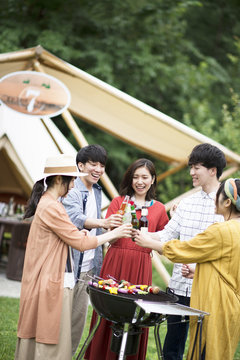 グランピングテントの前で乾杯をする若者たち