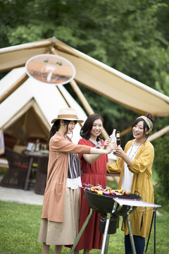 グランピングテントの前で乾杯をする若者たち