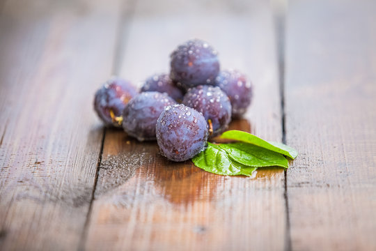 Organic plums with raindrops,rustic background
