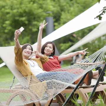 リクライニングチェアに座り自撮りをする2人の女性